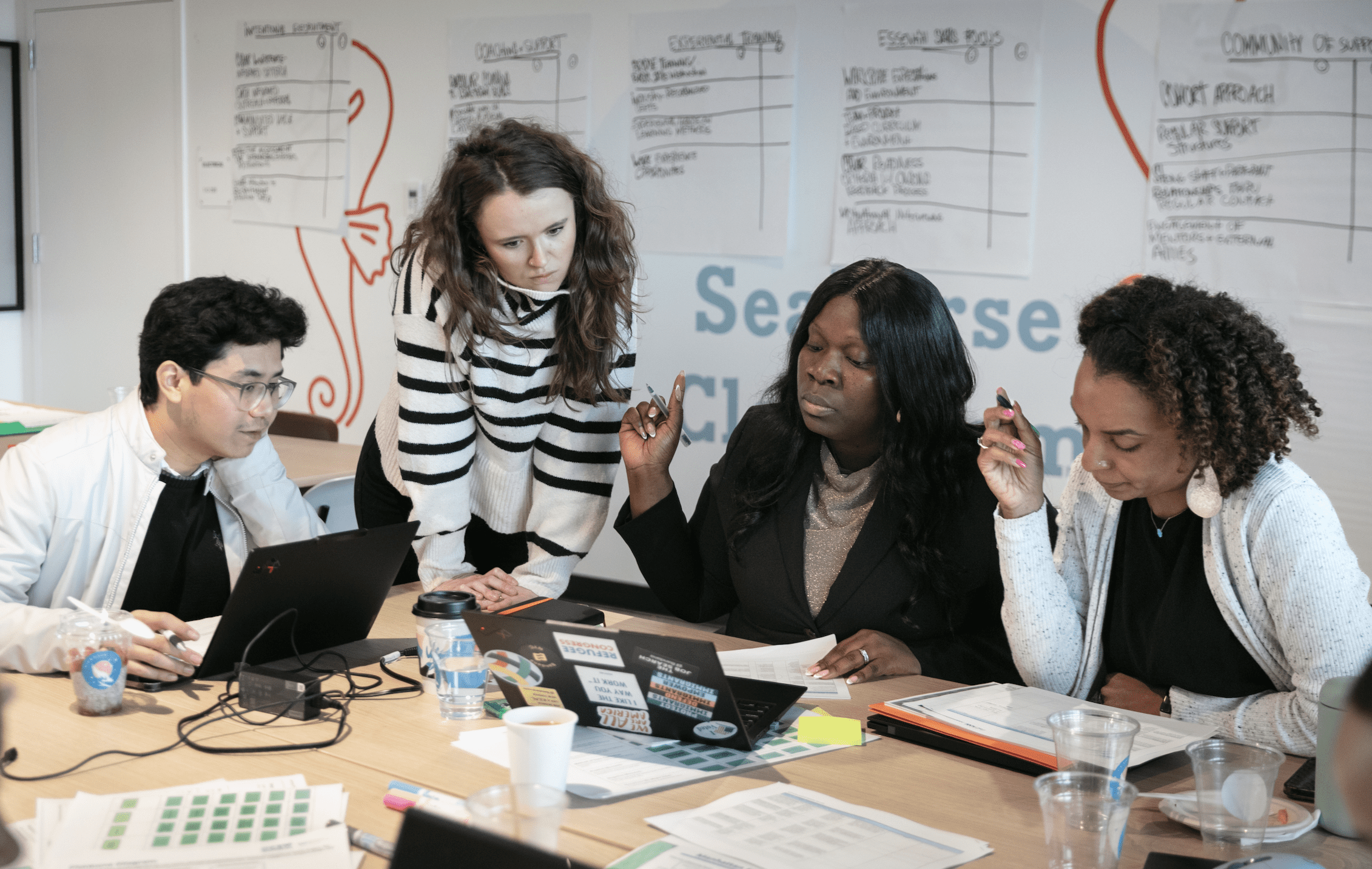 Professionals in discussion at a table in a classroom space.